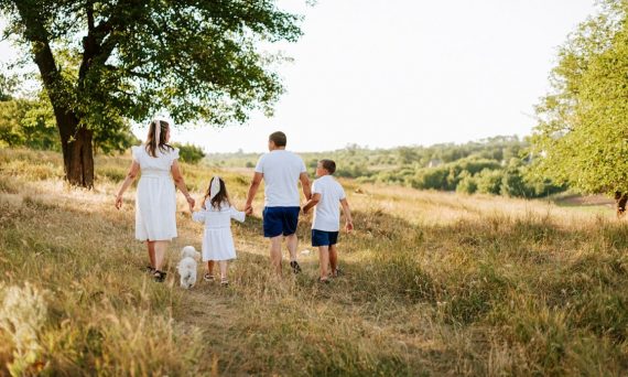 A family walking through a field with a dog
