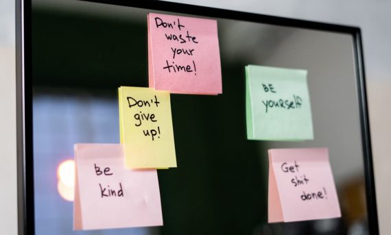 Colorful sticky notes with motivational messages on a mirror reflecting positivity.